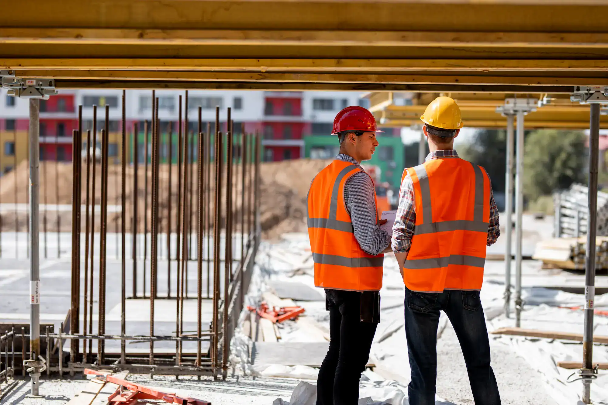 Byggeri under opførelse med to arbejdere i sikkerhedsudstyr.